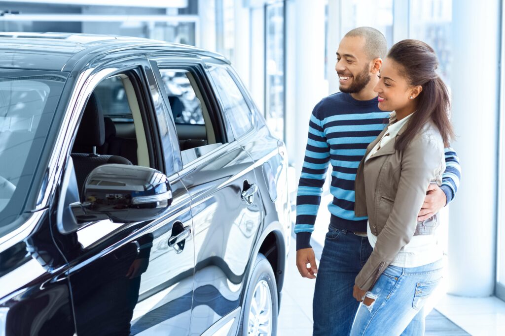 A man and woman looking at a car in a showroom.